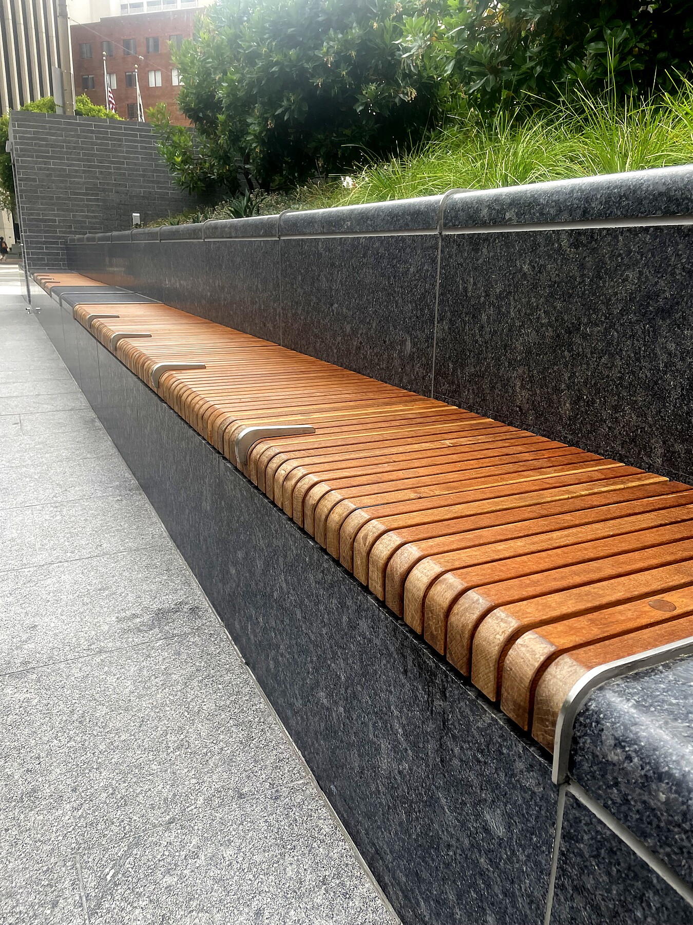 Wood bench topper with skate-stop clips along a walking path